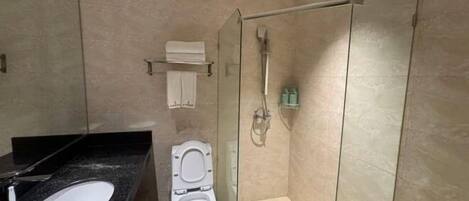 Ein modernes Badezimmer mit einer Duschkabine, einer weißen Toilette und einer schwarzen Ablage mit Waschbecken.