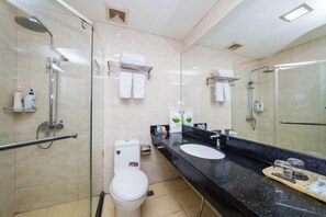 A modern bathroom with a glass shower enclosure, a white toilet, a black countertop with a sink and mirror, and a towel rack. - Xiangtan Jinguiyuan Hotel (Government City Wanda Plaza) (Xiangtan)