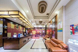 Un hall de hotel con mostrador de recepción, zona de estar y un techo decorativo.