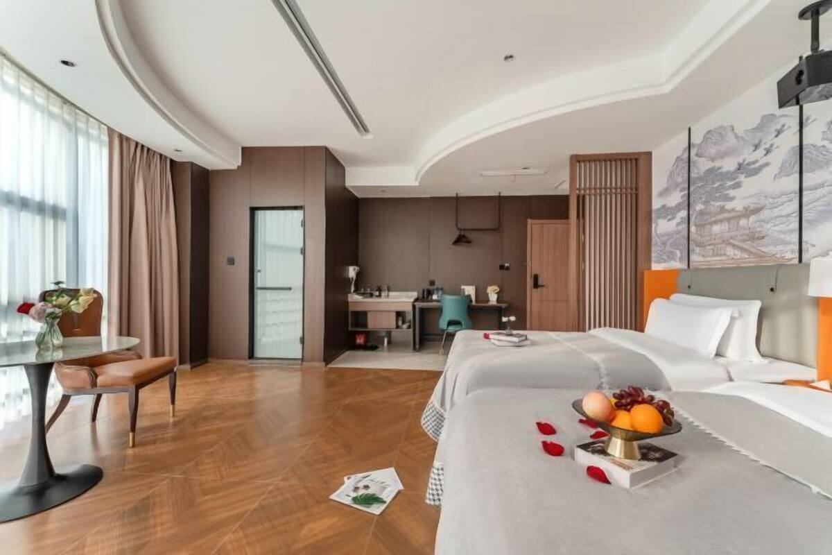 A hotel room with a bed, a desk, a chair, and a dining table.