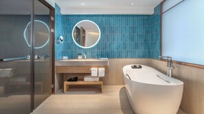 A modern bathroom with a freestanding bathtub, a vanity with a mirror, and a glass shower enclosure.