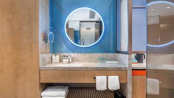 Un baño moderno con un mueble de tocador de madera, un espejo redondo y un lavabo empotrado.