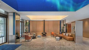A modern living room with a fireplace, comfortable seating, and large windows.