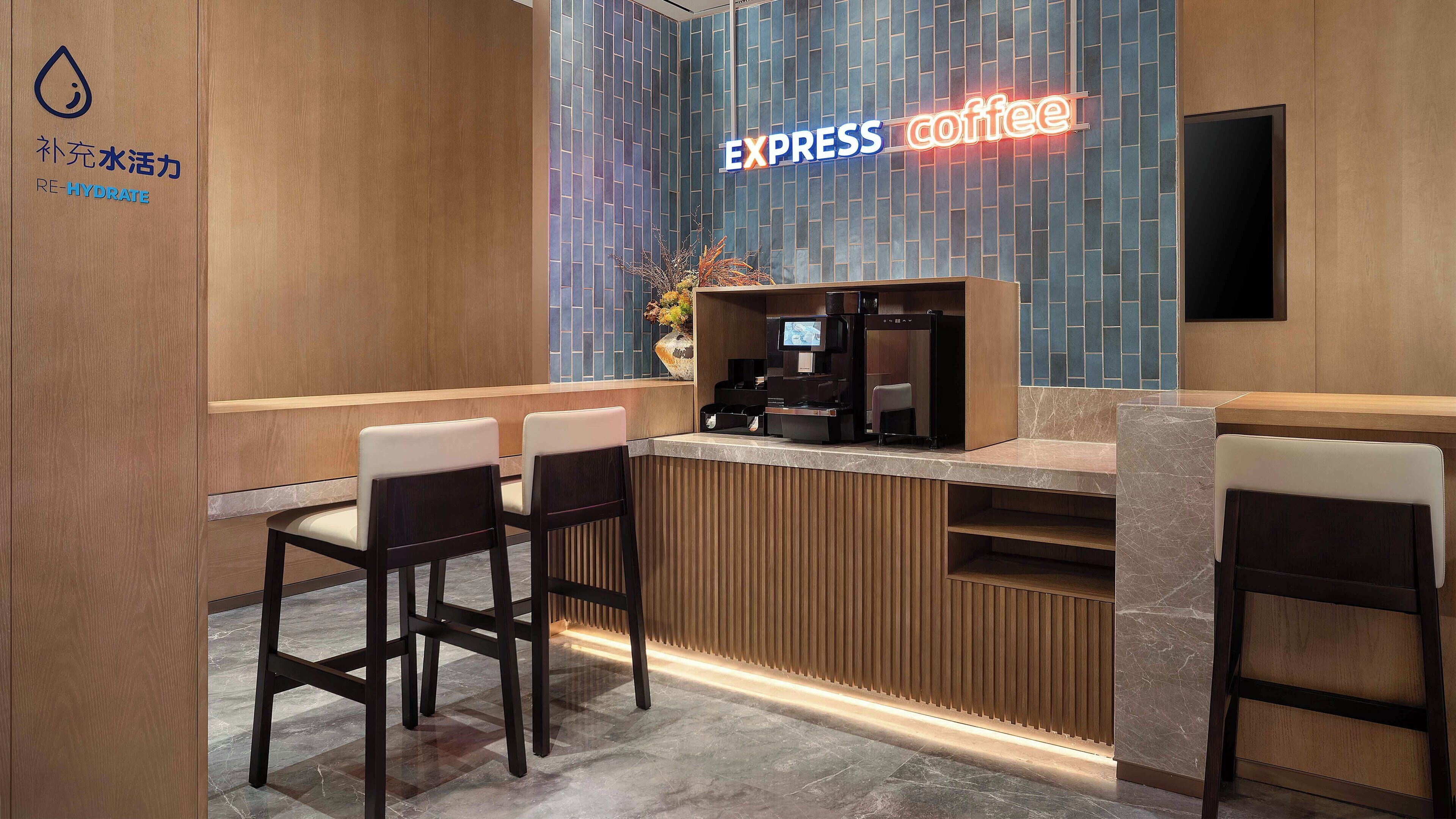 A modern coffee shop interior with a wooden reception desk, two bar stools, and a neon sign reading "EXPRESS coffee".