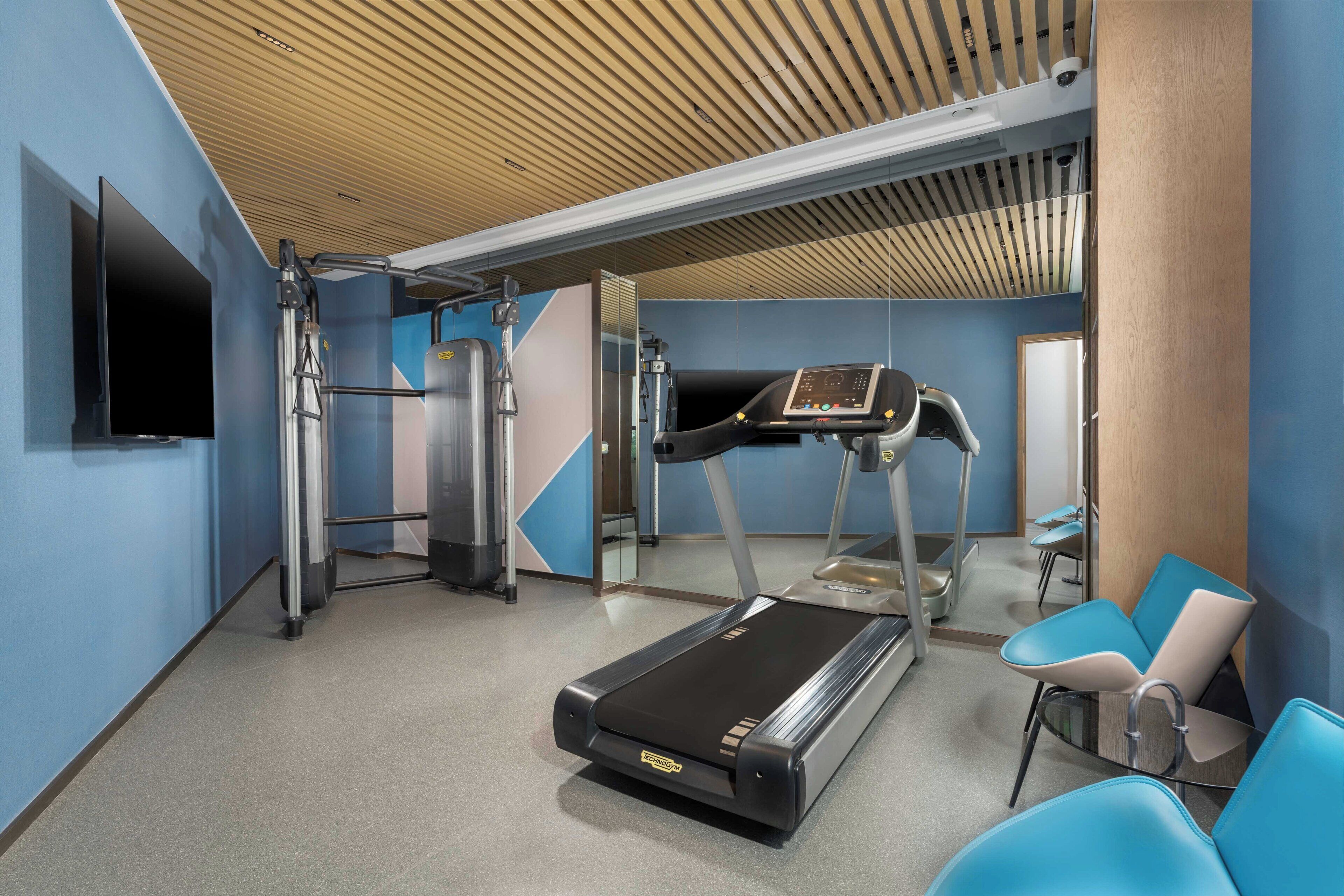 A modern fitness center with a treadmill, elliptical, and weight machines.