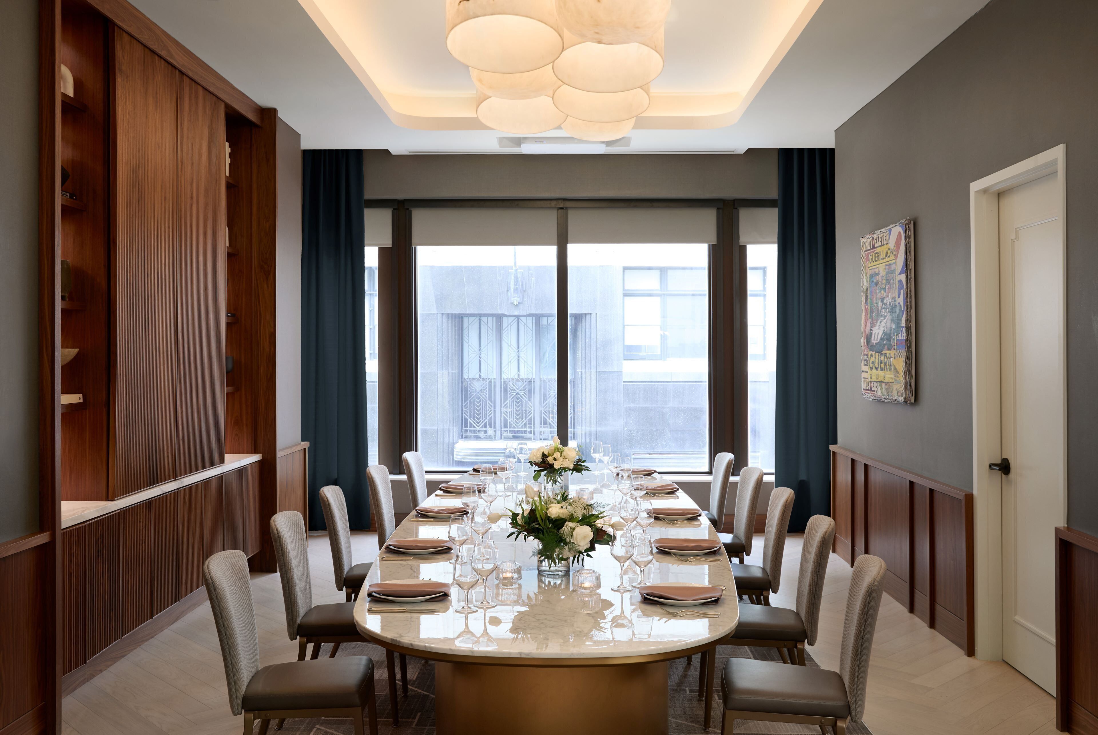 A dining area with a long table set for a meal, large windows, and a modern interior design.