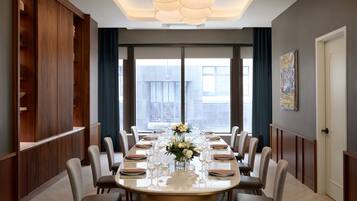 A dining area with a long table set for a meal, large windows, and a modern interior design.