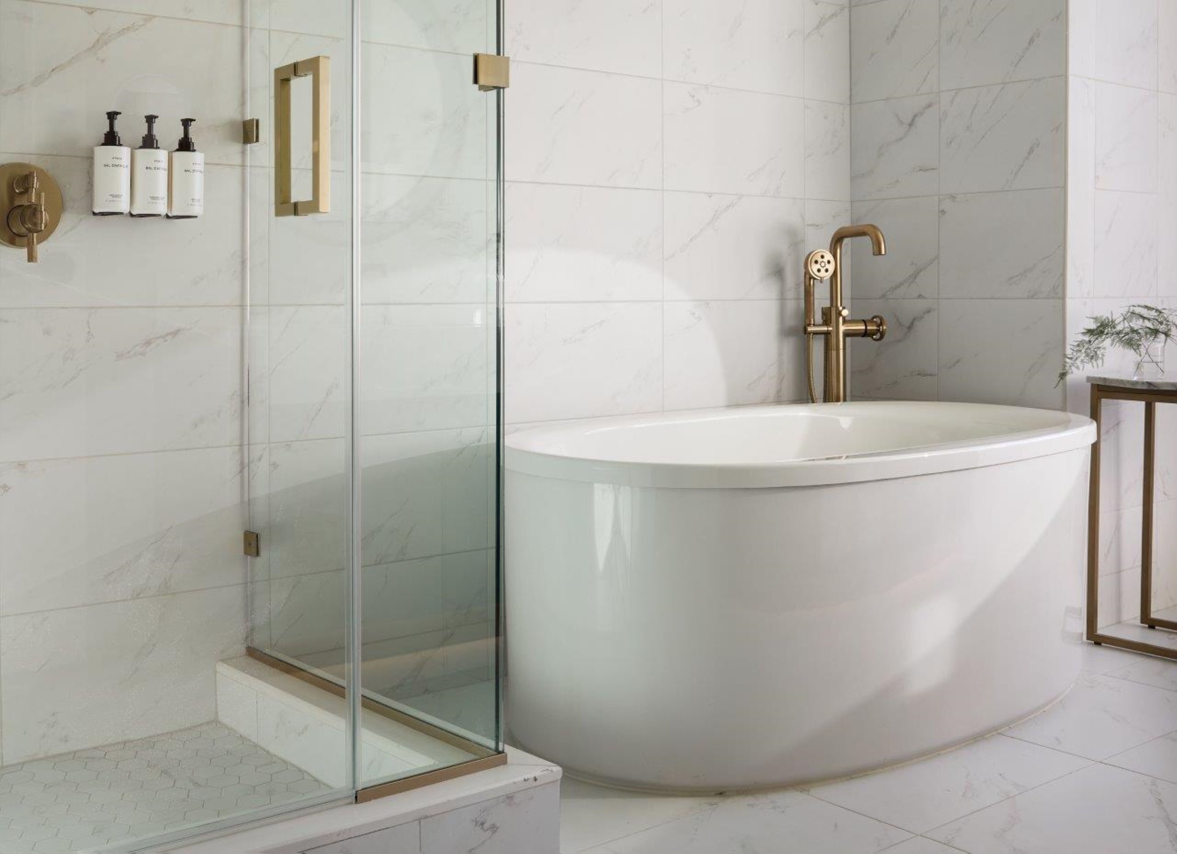 A modern bathroom with a freestanding bathtub, a glass shower enclosure, and a marble-tiled wall.