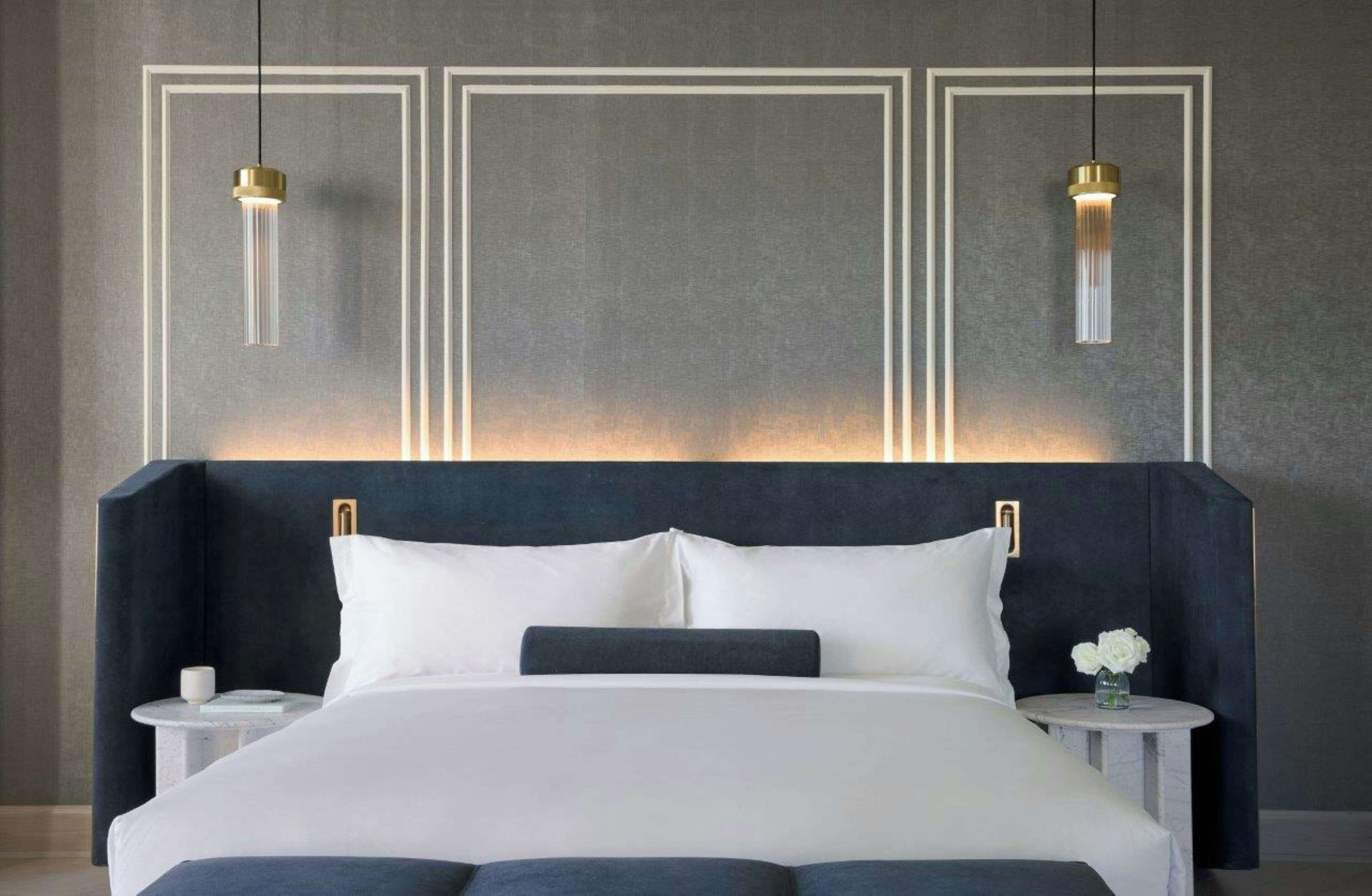 A modern bedroom with a large bed, two bedside tables, and pendant lights.