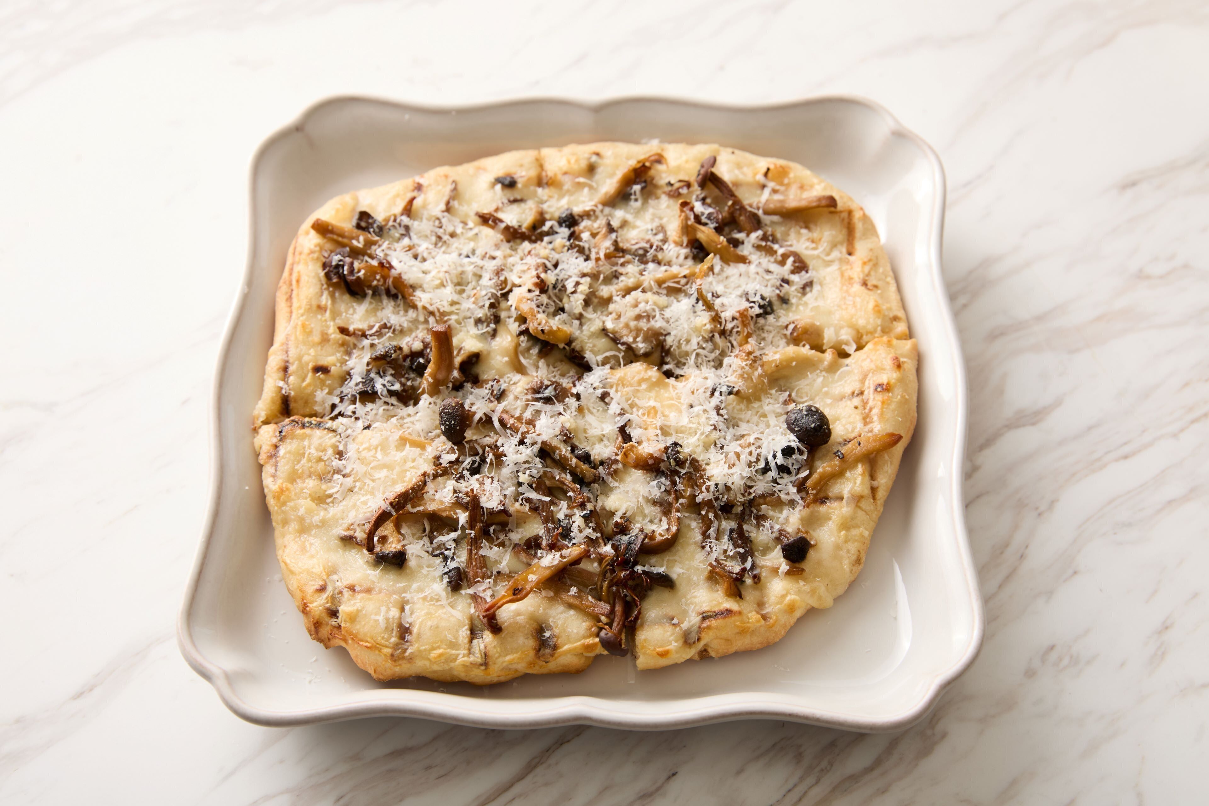 Una pizza sobre un plato de cerámica blanca.