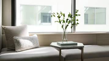 A modern living room with a sofa, a small table, and a vase with green plants.