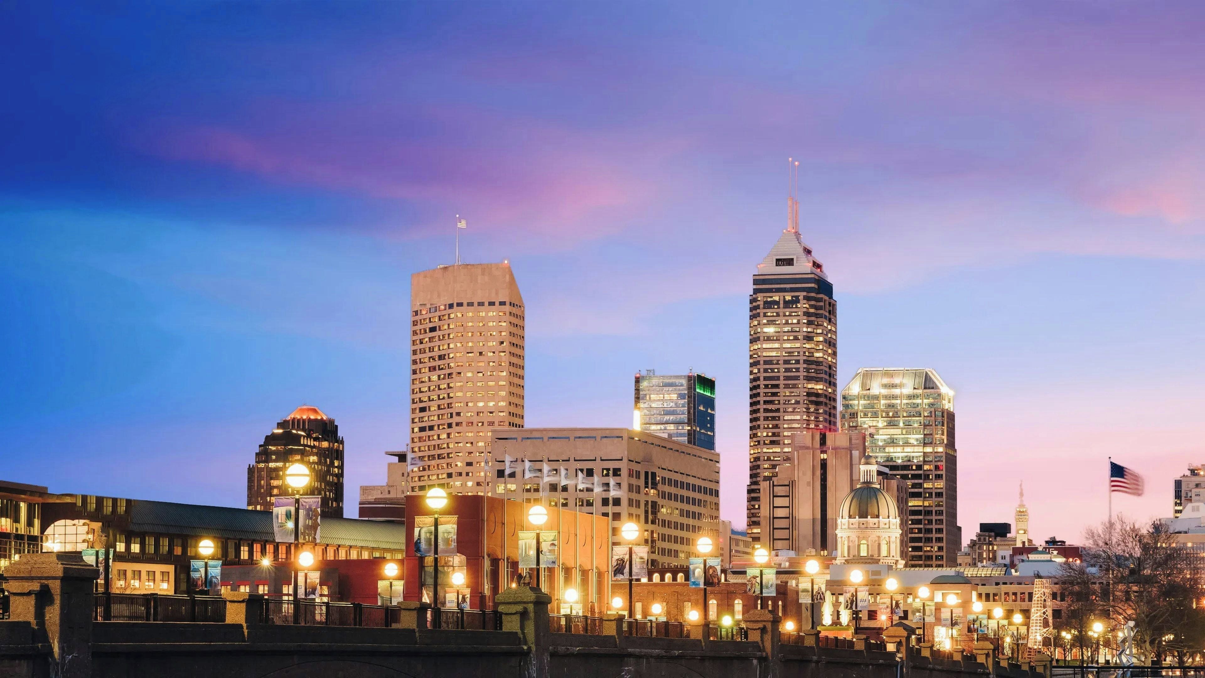 A city skyline with illuminated buildings and a clear sky.