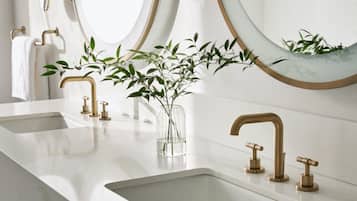 A bathroom with two sinks, gold faucets, and a mirror with a wooden frame.