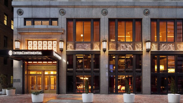 A hotel entrance with a marquee sign, large windows, and potted plants. - InterContinental Indianapolis by IHG (Indianapolis)