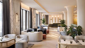 A modern hotel lobby with seating areas, marble walls, and large windows. - InterContinental Indianapolis by IHG (Indianapolis)