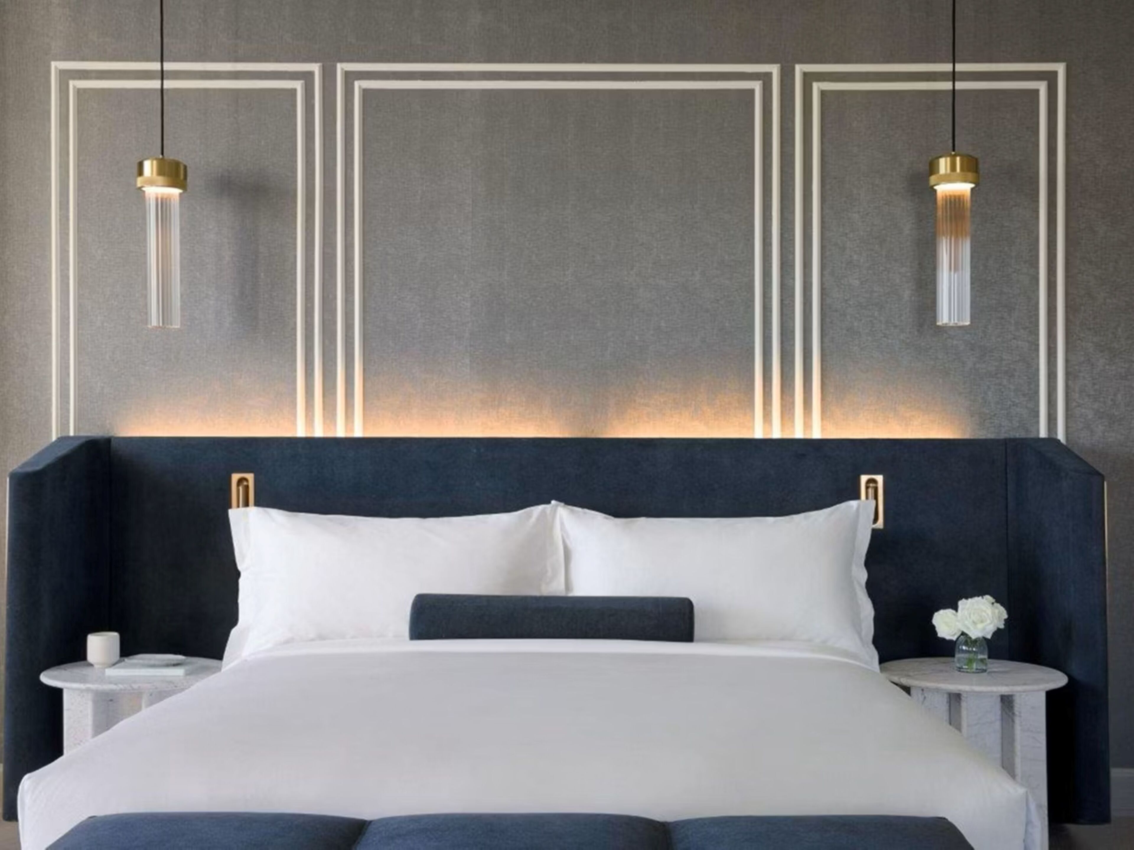 Ein modernes Schlafzimmer mit einem großen Bett, zwei Nachttischen und Pendelleuchten.