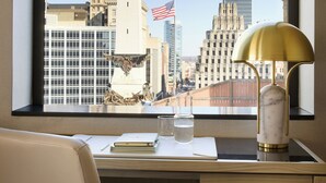 Un escritorio con vistas a un paisaje urbano, que incluye un edificio alto con una estatua en la cima e la bandera estadounidense.
