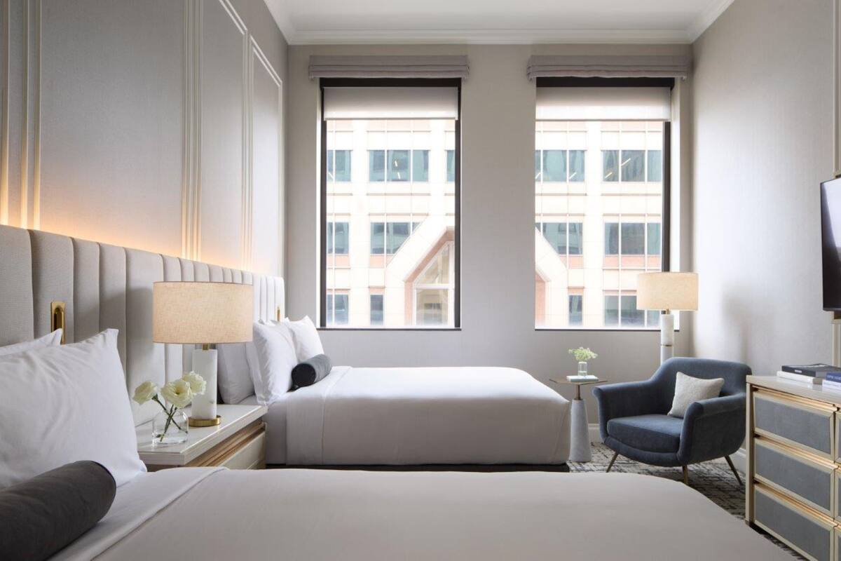Una habitación de hotel con dos camas, televisión, escritorio y una silla.