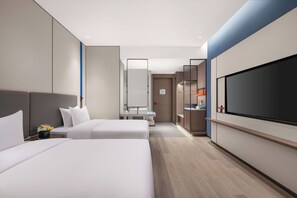 A modern hotel room with two beds, a large flat-screen TV, a vanity with a mirror, and a small bathroom. - Holiday Inn Express Hai'an Railway Station by IHG (Nantong)
