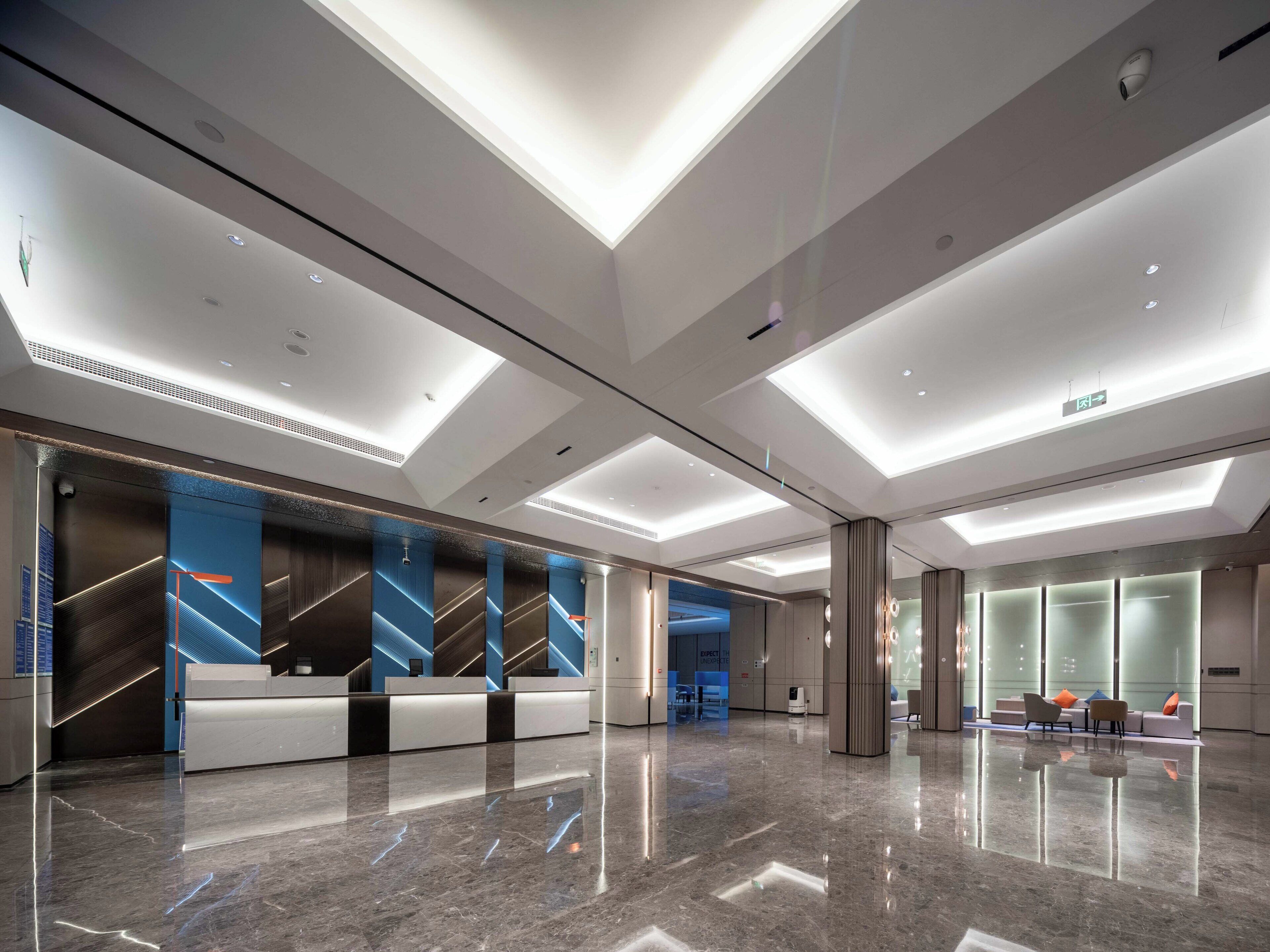 Een moderne lobby met een receptiebalie, een zithoek en een glazen scheidingswand.