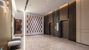 Un hall d’entrée moderne avec un motif à carreaux sur le mur, un espace salon et un comptoir d’accueil.