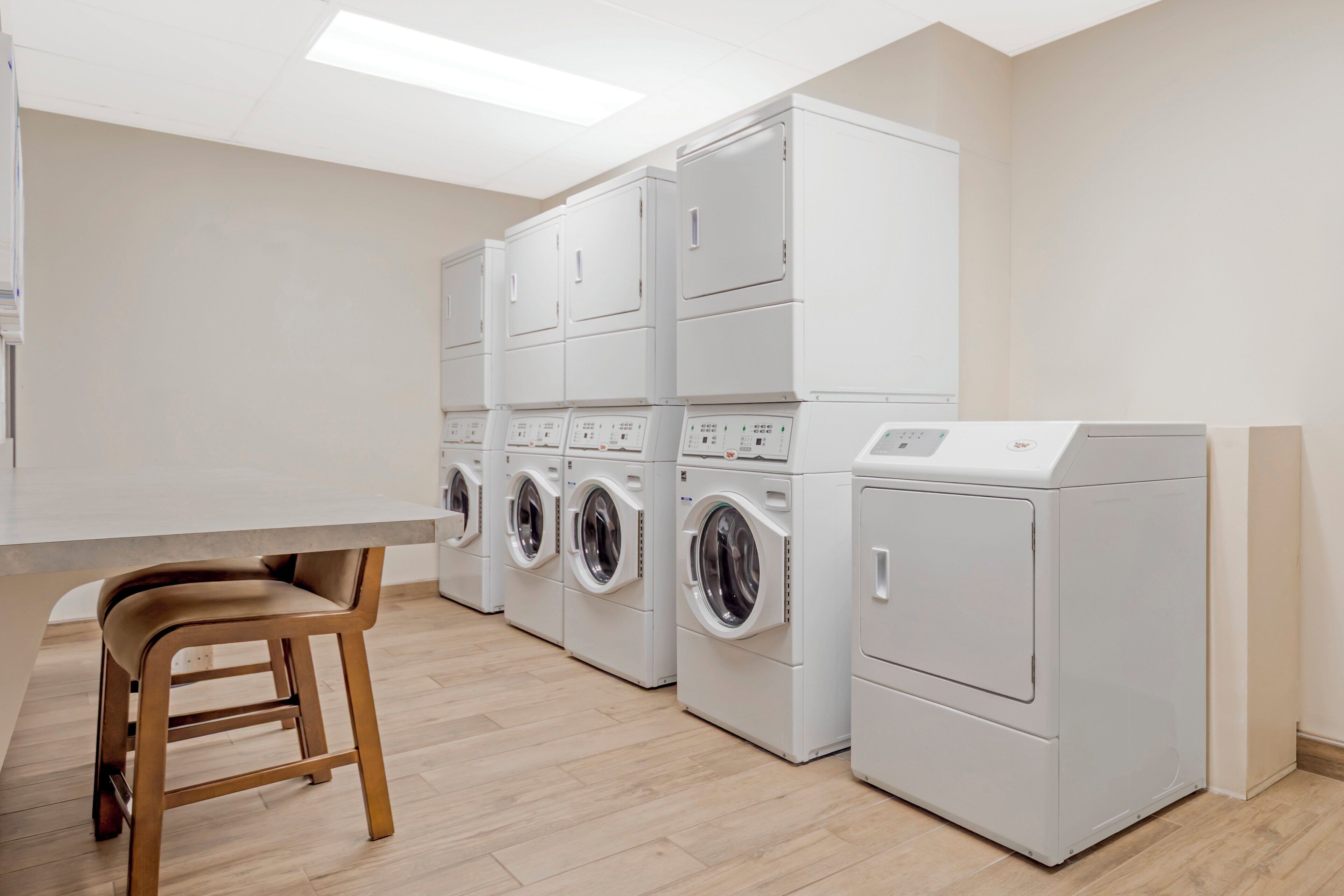 A laundry room with stacked washing machines and a single dryer.