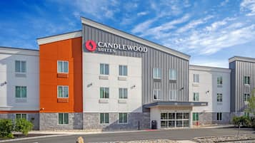 A modern hotel with a prominent "Candlewood Suites" sign, a stone facade, and a parking lot.