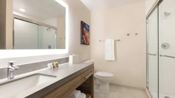 A modern bathroom with a glass-enclosed shower, a large mirror, and a toilet.