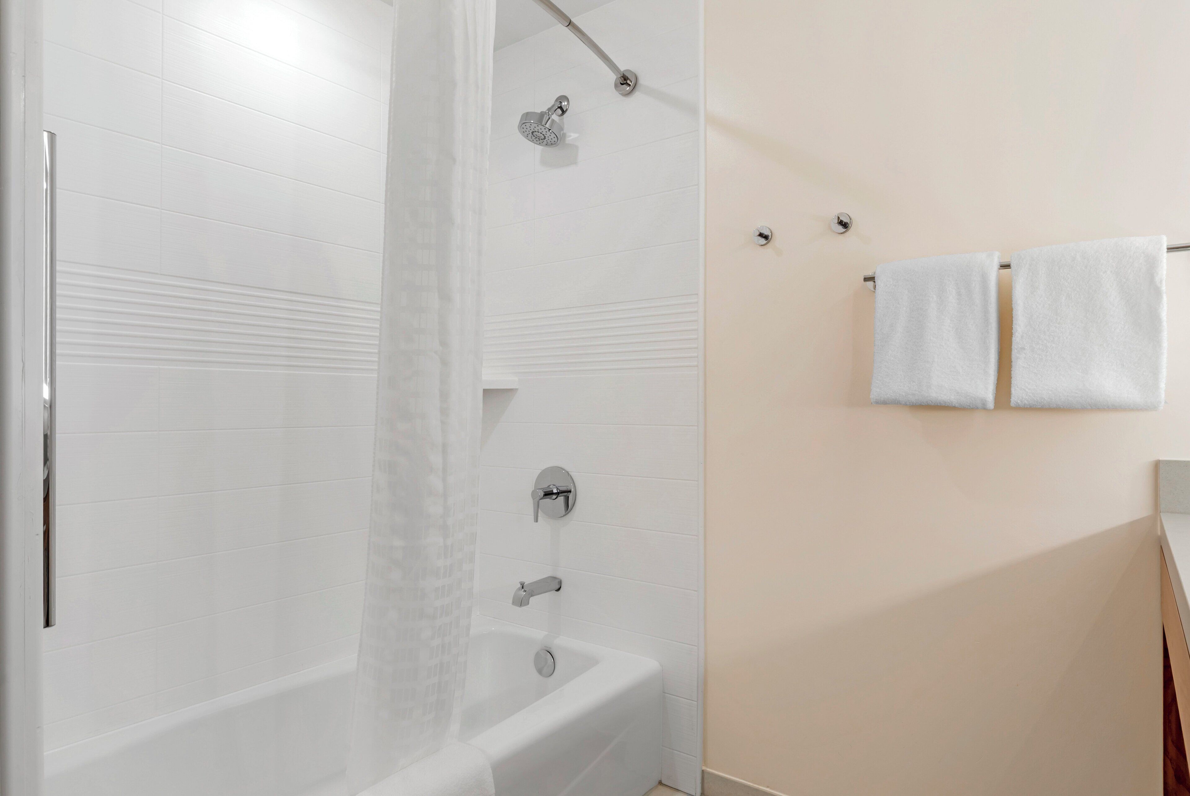 Un baño moderno con bañera, ducha y perchero para toallas.