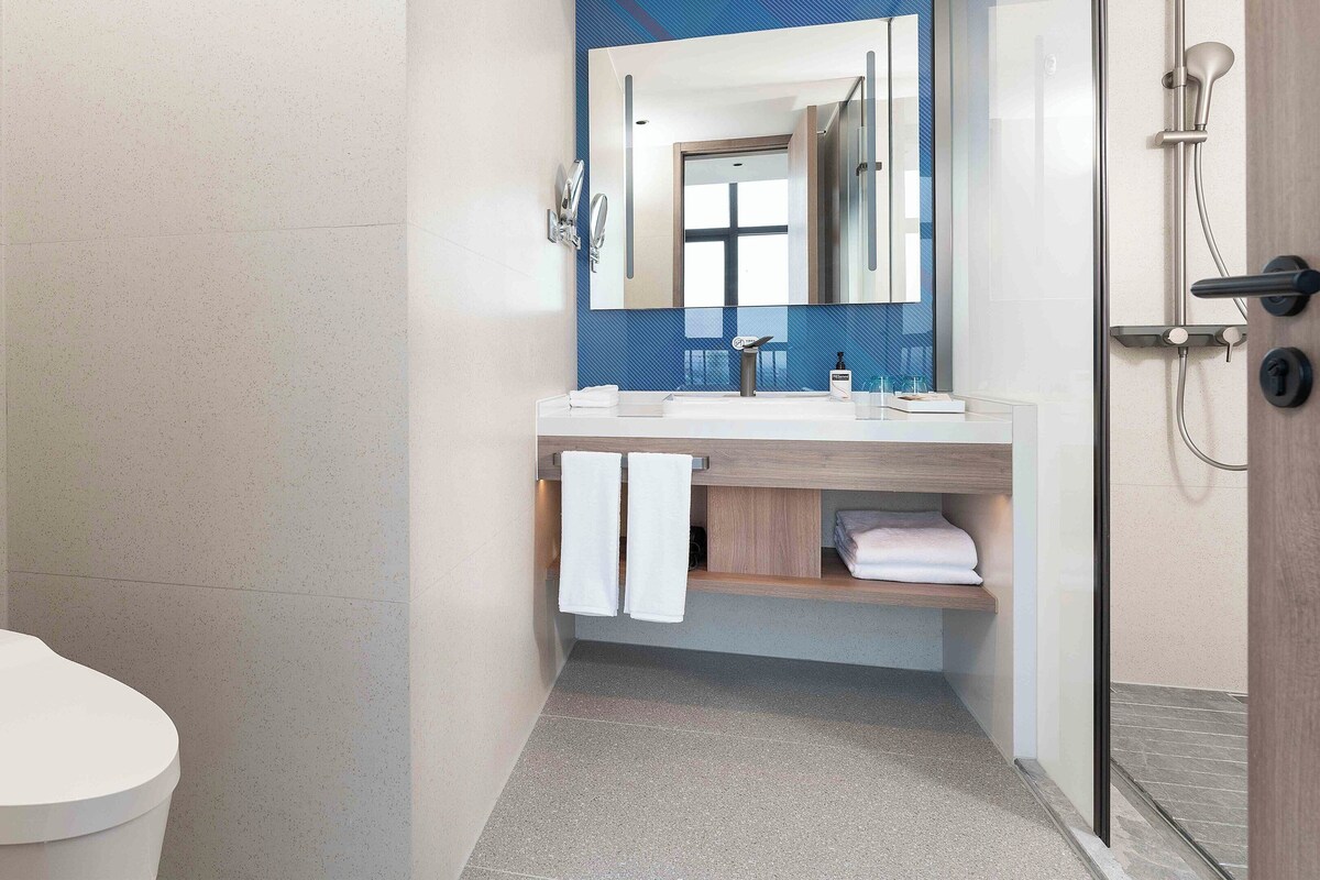 A modern bathroom with a toilet, a sink with a mirror, and a shower.
