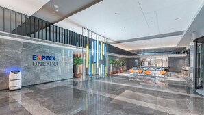 A modern lobby with a marble floor, a reception desk, and seating area with orange chairs. - Holiday Inn Express Foshan Shunde Lecong (Foshan)