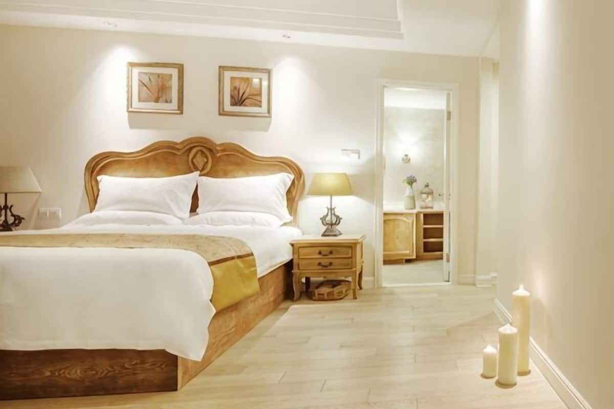 A bedroom with a wooden bed, bedside tables, a nightstand, and a mirror.