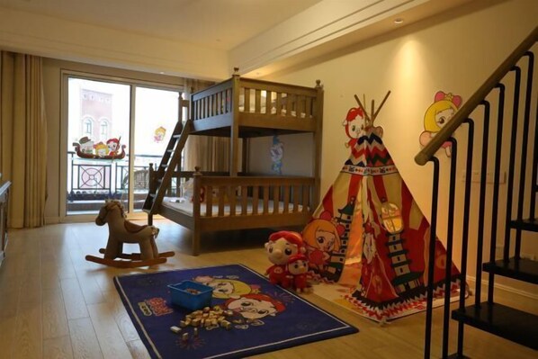 Una sala de juegos para niños con una litera, juguetes y un tapete colorido.