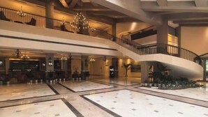 Un vestíbulo amplio con suelo de mármol, una escalera monumental y varios niveles con balcones.