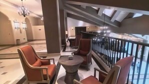 Un moderno vestíbulo de hotel con un área de descanso que incluye sillones de cuero y una mesa redonda.