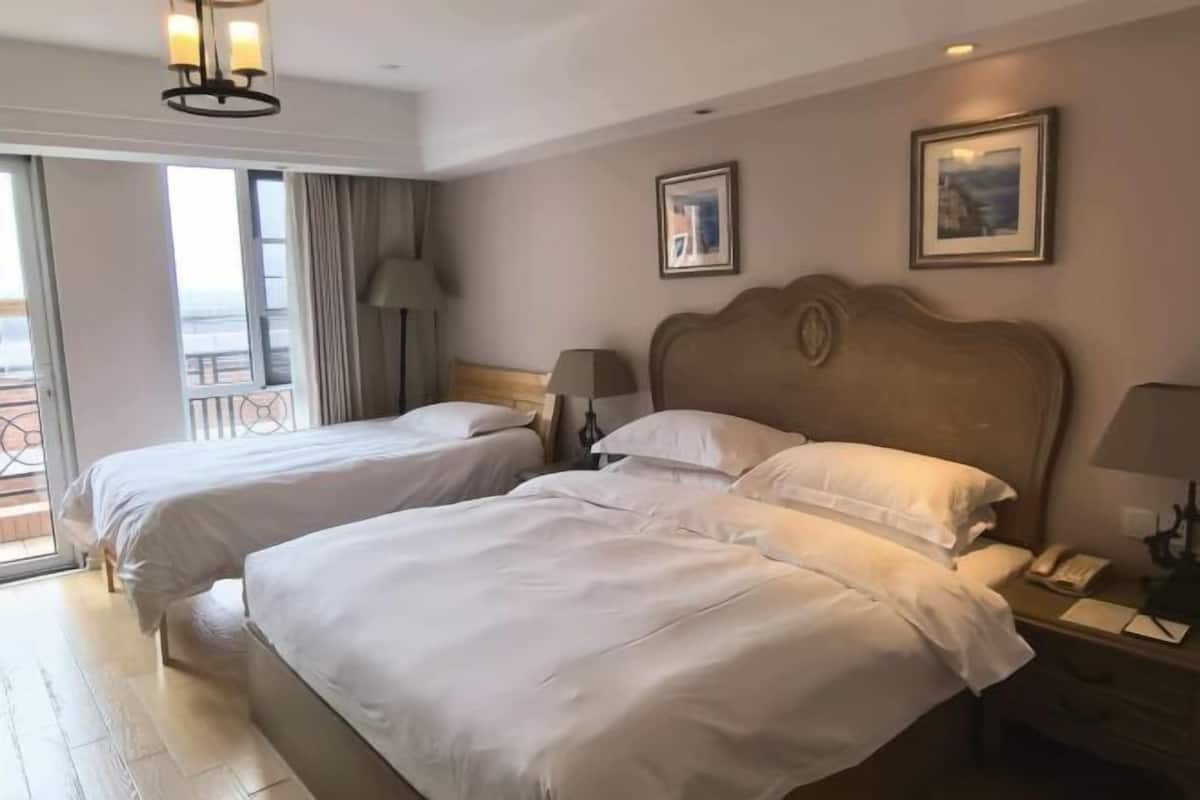 A hotel room with two beds, a balcony, a wooden headboard, and a nightstand with a lamp.