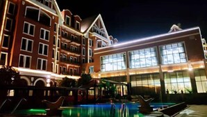 Un hotel con un amplio área de piscina, varios balcones y grandes ventanales.