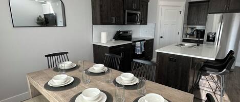A modern kitchen with dark cabinets, a microwave, and a refrigerator.
