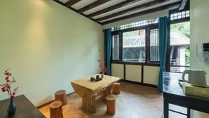 A room with a wooden table and stools, a window with a view of traditional architecture, and a ceiling with exposed beams. - Youtang Cloud Station CourtyardZen-style Inn (Lijiang Shuhe Ancient Town Branch) (Lijiang)