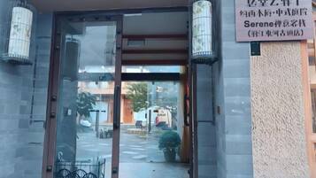 A hotel entrance with a glass door, a signboard, and two lantern-style lights.