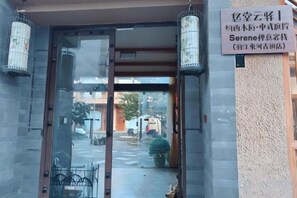A hotel entrance with a glass door, a signboard, and two lantern-style lights. - Youtang Cloud Station CourtyardZen-style Inn (Lijiang Shuhe Ancient Town Branch) (Lijiang)