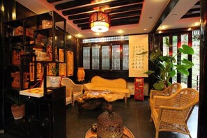 A traditional room with a sofa, wicker chairs, a decorative table, and a bookshelf with various items. - Youtang Cloud Station CourtyardZen-style Inn (Lijiang Shuhe Ancient Town Branch) (Lijiang)