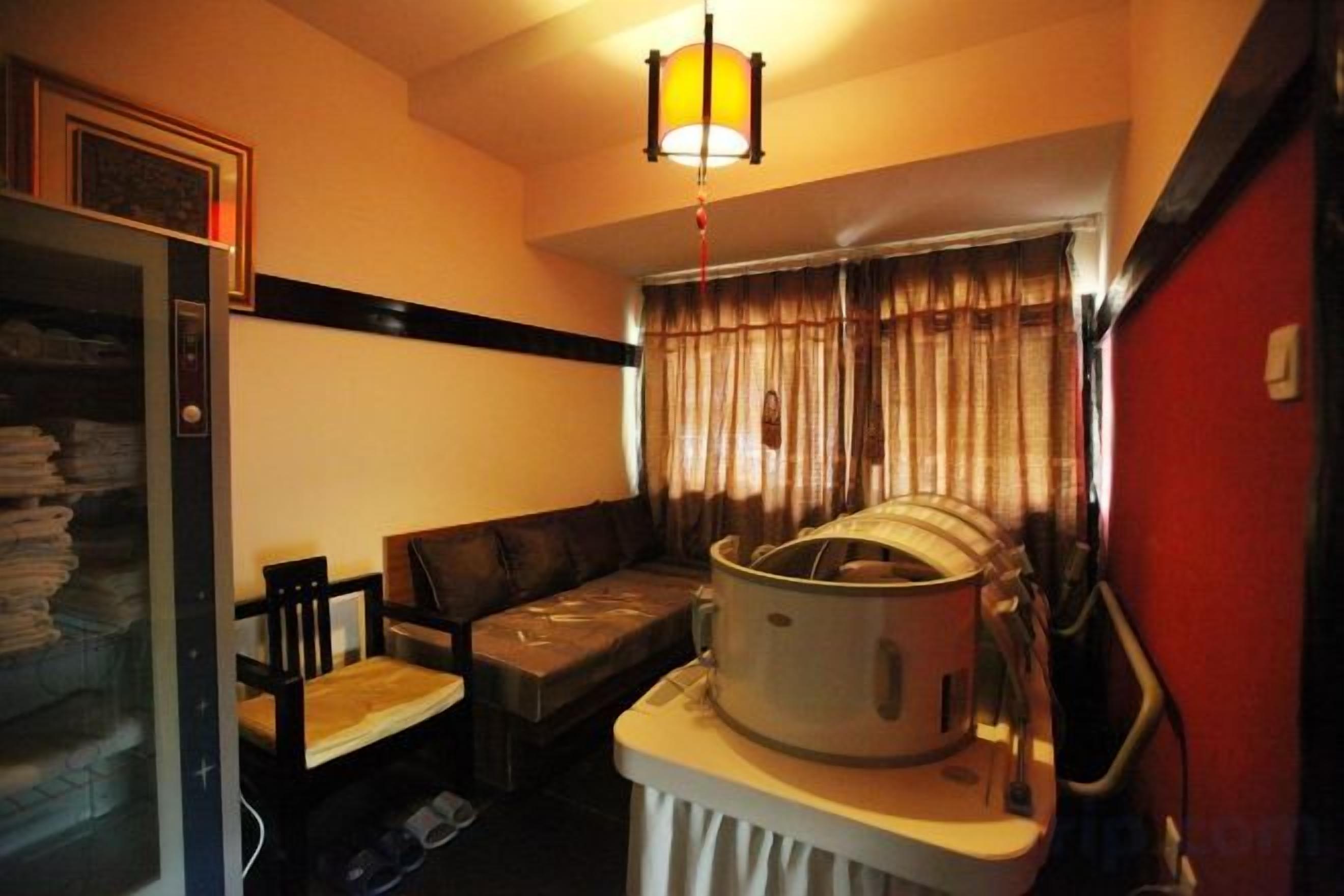 Habitación con sofá, mesa, hervidor y ventana con cortinas.