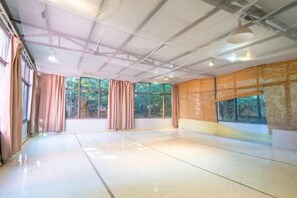 Una habitación espaciosa con ventanas amplias, piso pulido y techo alto con vigas a la vista.