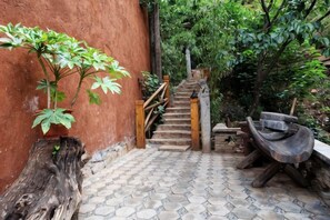 Una escalera conduce a una terraza de madera con un banco rústico y un pozo de fuego.