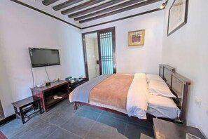 A bedroom with a bed, a TV, a desk, and a mirror. - Youtang Cloud Station CourtyardZen-style Inn (Lijiang Shuhe Ancient Town Branch) (Lijiang)