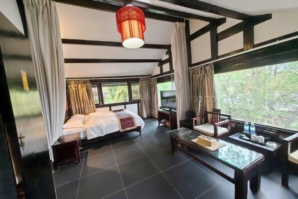 A room with a bed, a glass coffee table, and a view of greenery outside. - Youtang Cloud Station CourtyardZen-style Inn (Lijiang Shuhe Ancient Town Branch) (Lijiang)