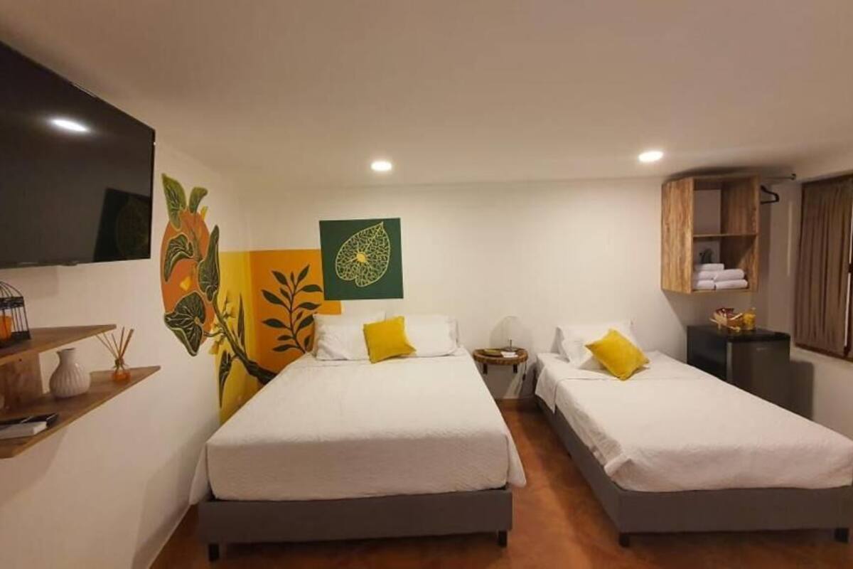 Una habitación con dos camas, un armario de madera, una mesita y decoración en la pared.