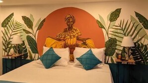 A bed with a mural of a seated figure, two pillows, and two bedside tables with lamps. - Candilejo Hotel Boutique (Cartagena)