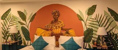 A bed with a mural of a seated figure, two pillows, and two bedside tables with lamps.
